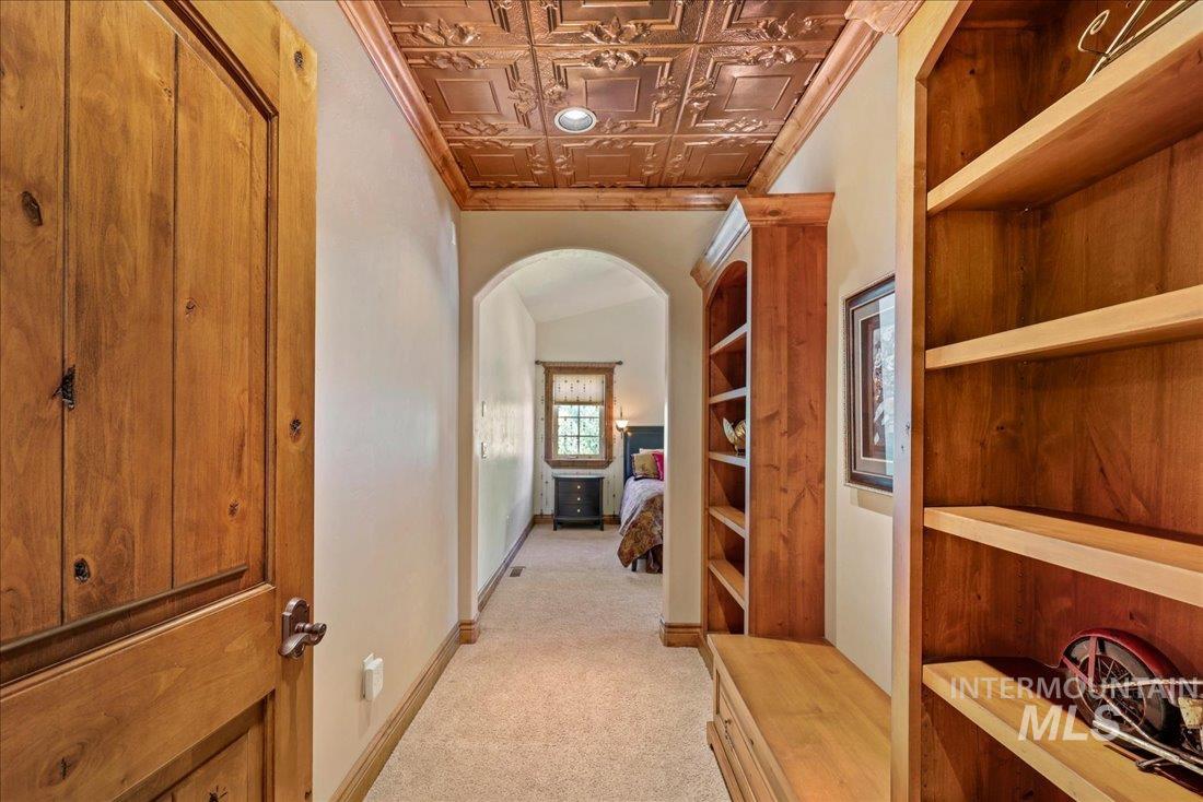 Corridor featuring arched walkways, an ornate ceiling, light carpet, and ornamental molding