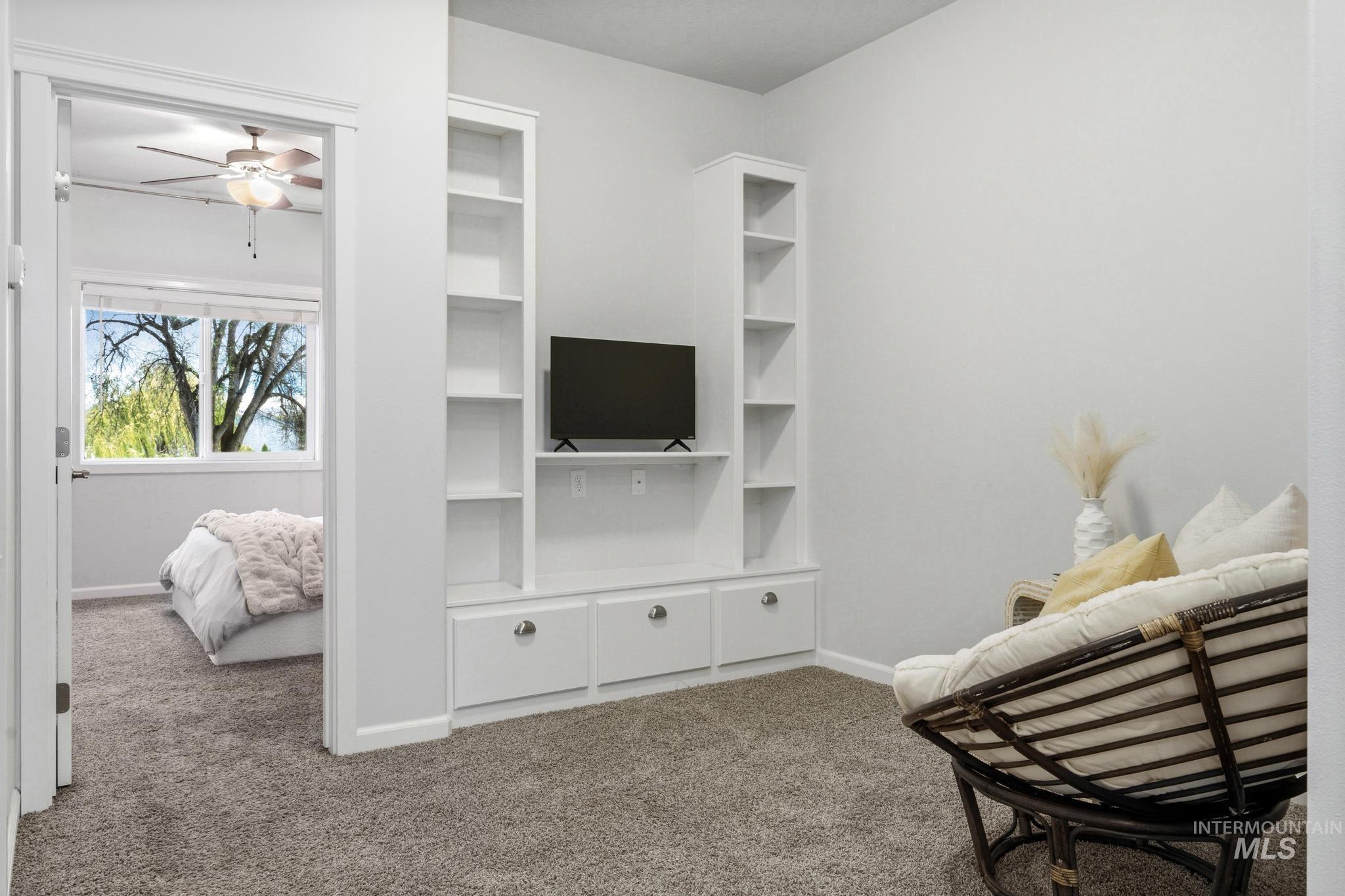 Sitting room with dark carpet and ceiling fan