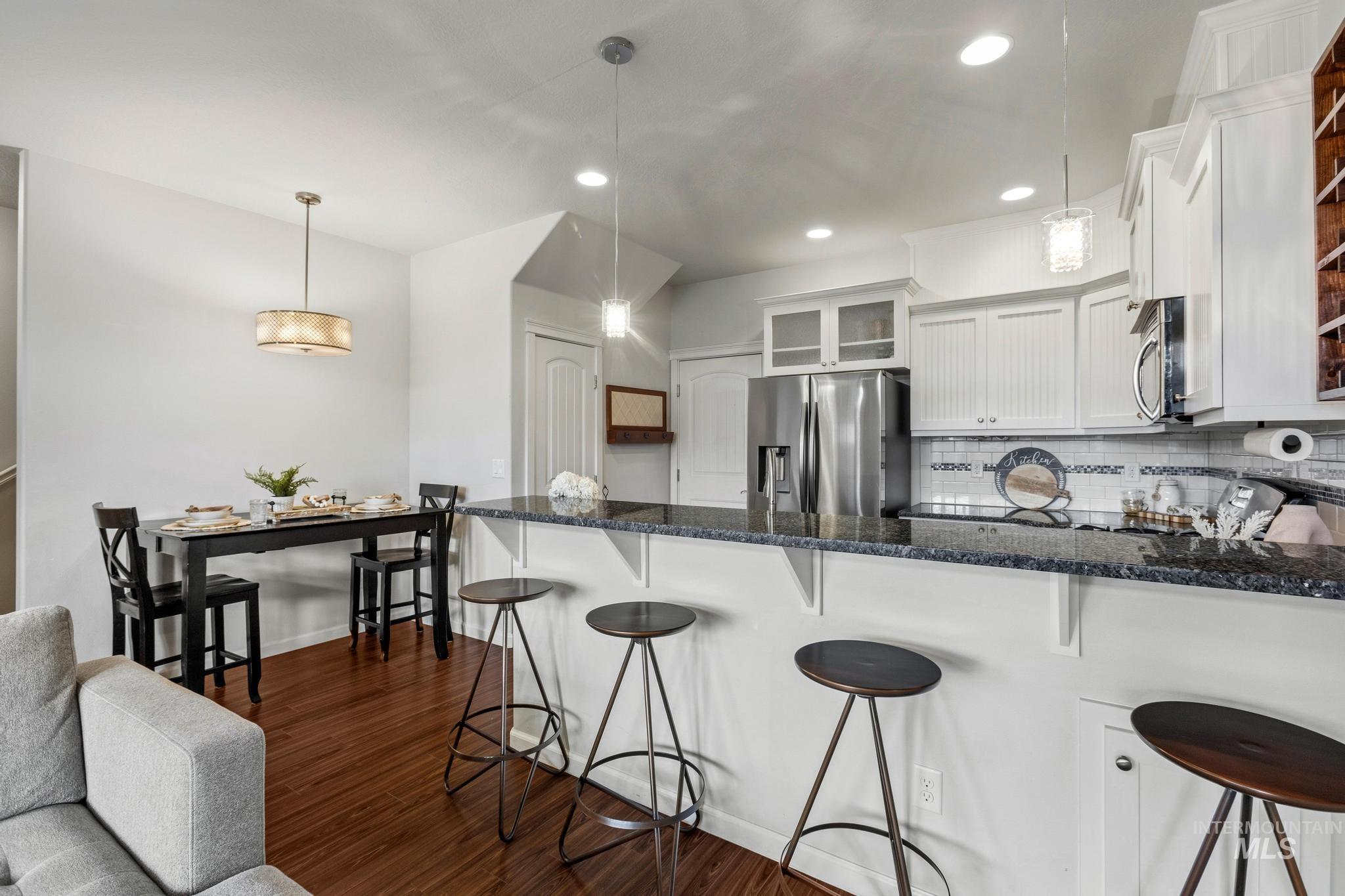 Kitchen with glass insert cabinets, a kitchen bar, white cabinets, a peninsula, and stainless steel appliances