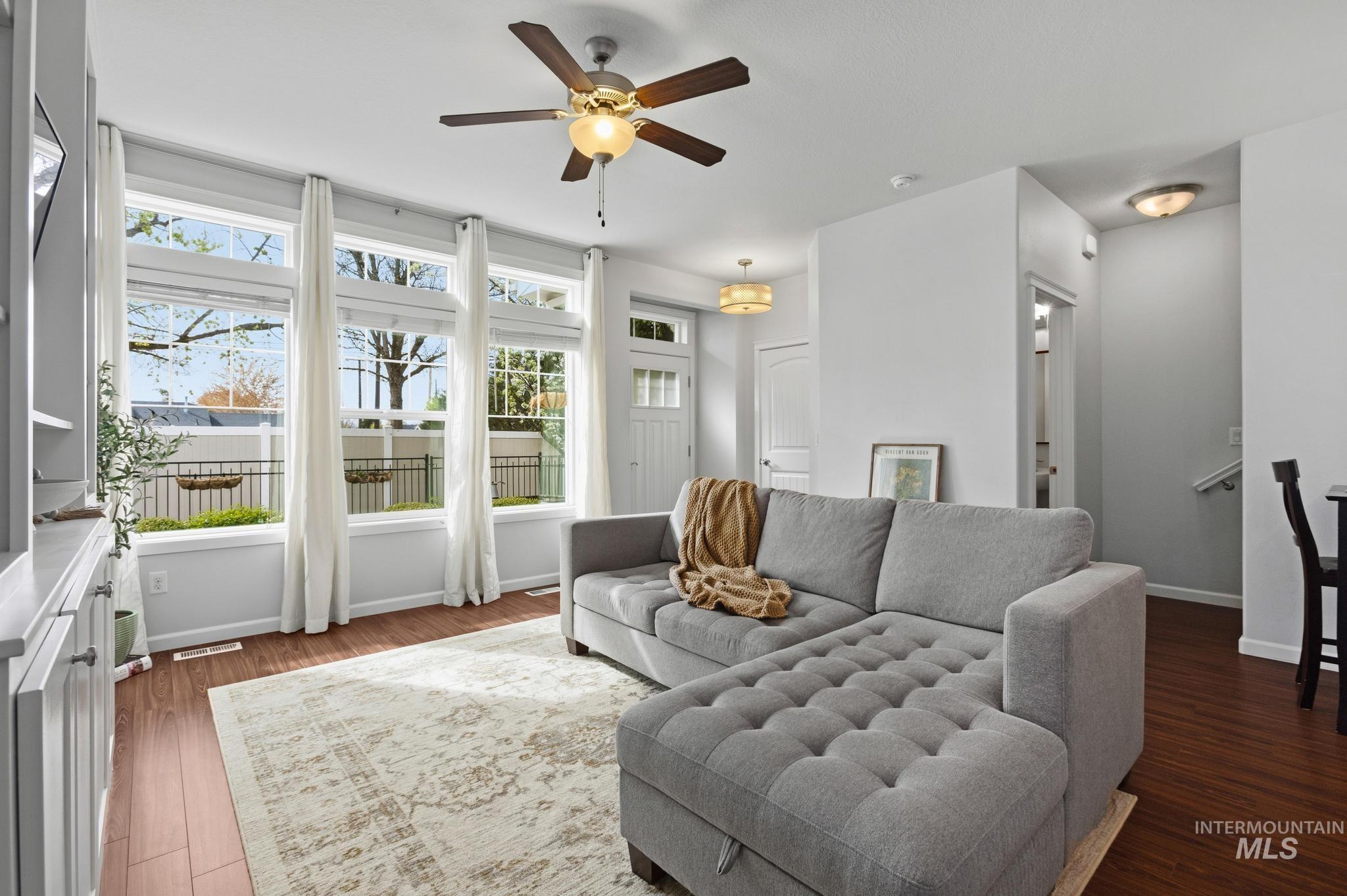 Living room featuring a ceiling fan and dark wood-type flooring