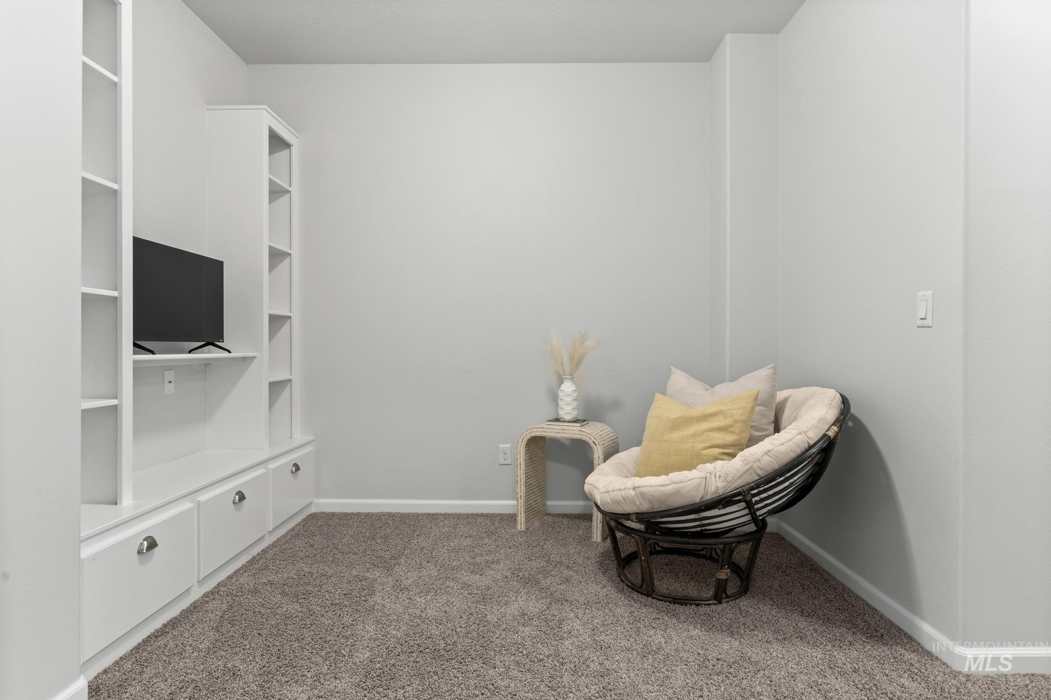 Sitting room with dark carpet and baseboards