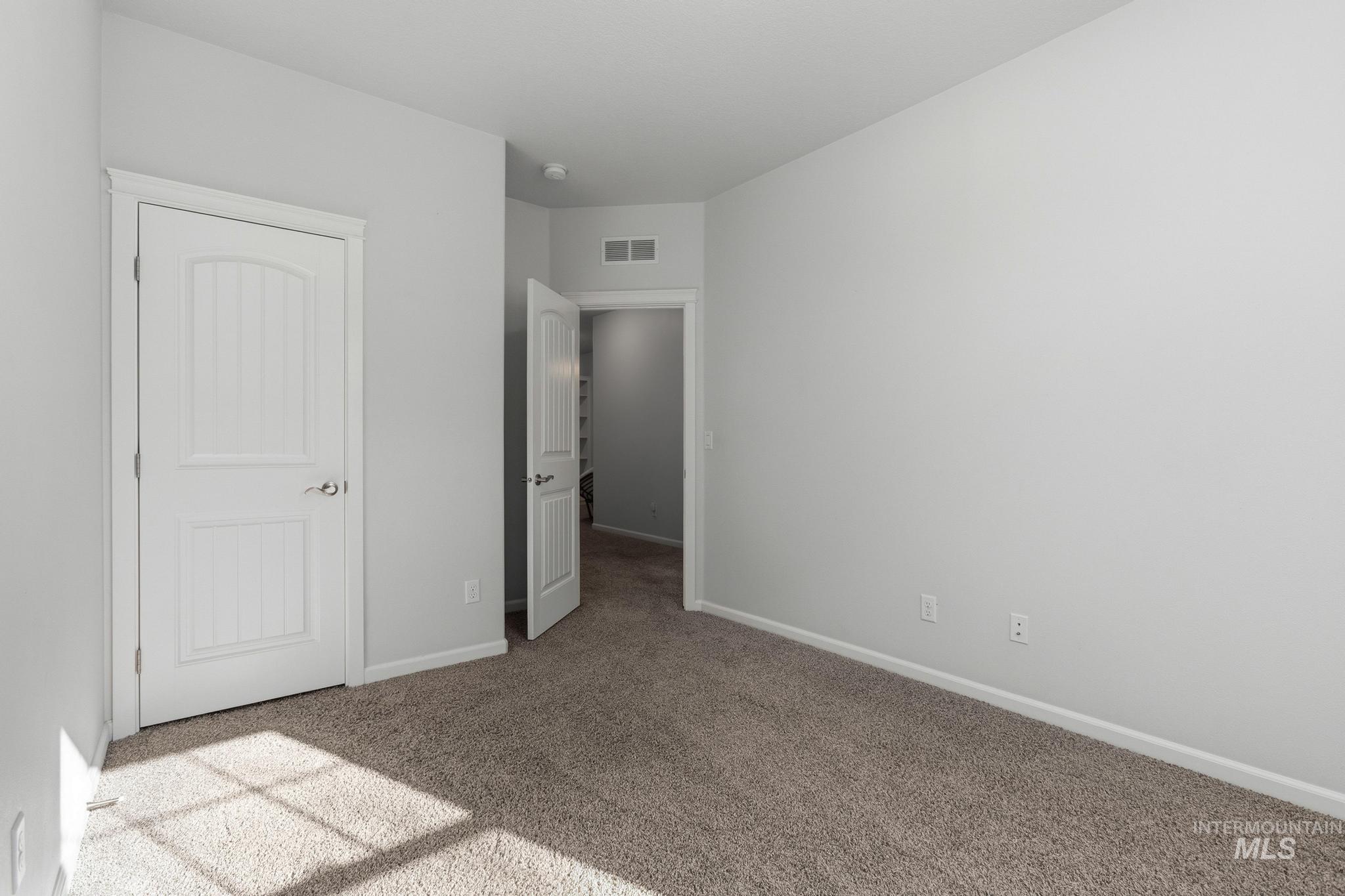 Unfurnished bedroom with light colored carpet and baseboards