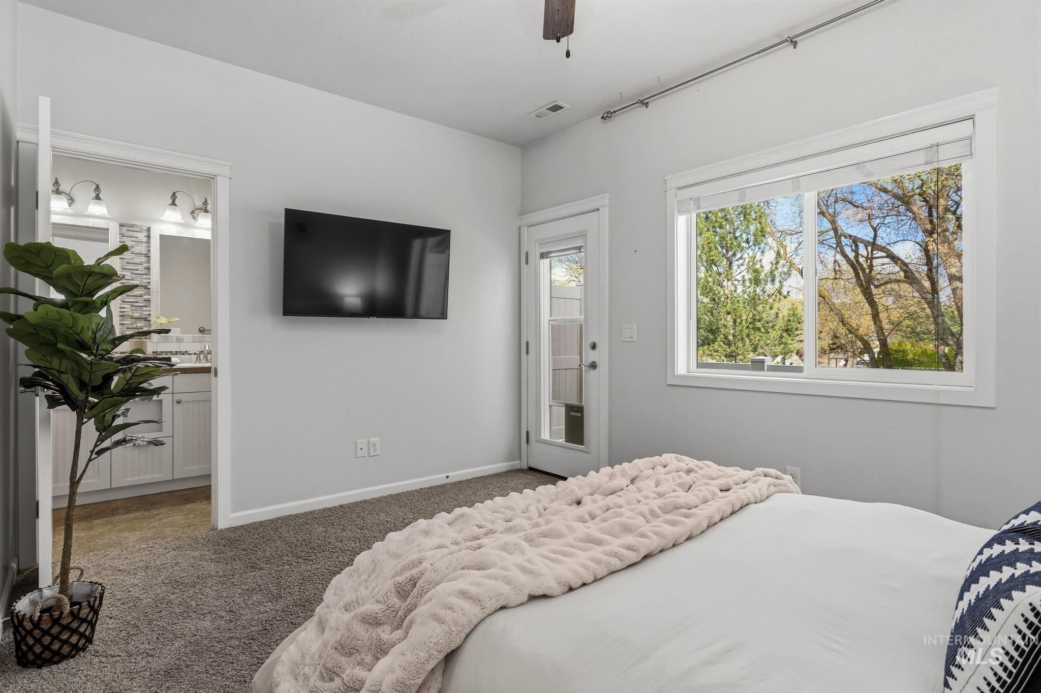 Carpeted bedroom featuring access to outside, ceiling fan, and ensuite bath