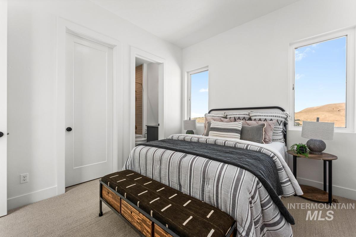 Bright bedroom featuring two windows, neutral carpet, and white paneled doors