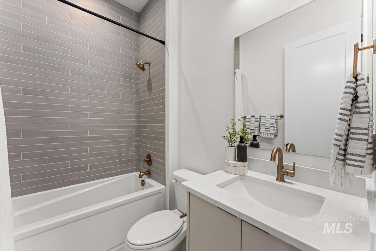 Contemporary bathroom featuring a tub/shower combination with gray subway tile surround and a toilet