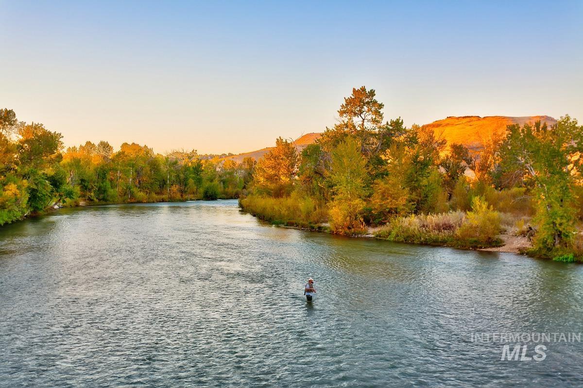 River frontage property featuring mature trees, a natural shoreline, and distant mountain scenery