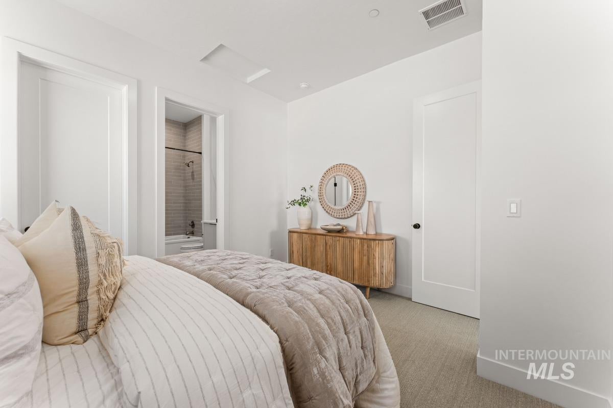 Bright interior space featuring a light-toned carpet, a full-lite interior door, and a second interior door opening to a bathroom with a tiled shower and bathtub