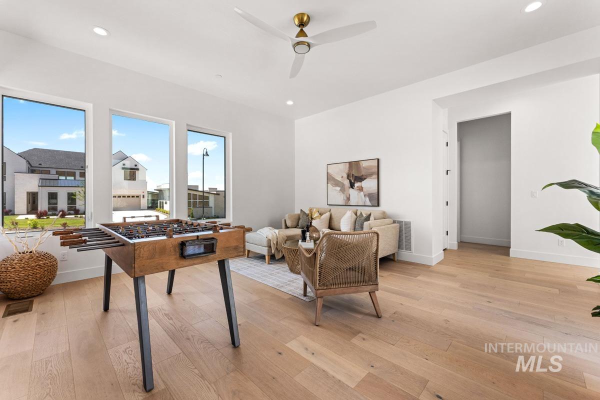 Bright interior space featuring light wood-finish flooring, recessed lighting, and a modern ceiling fan with a gold-tone accent