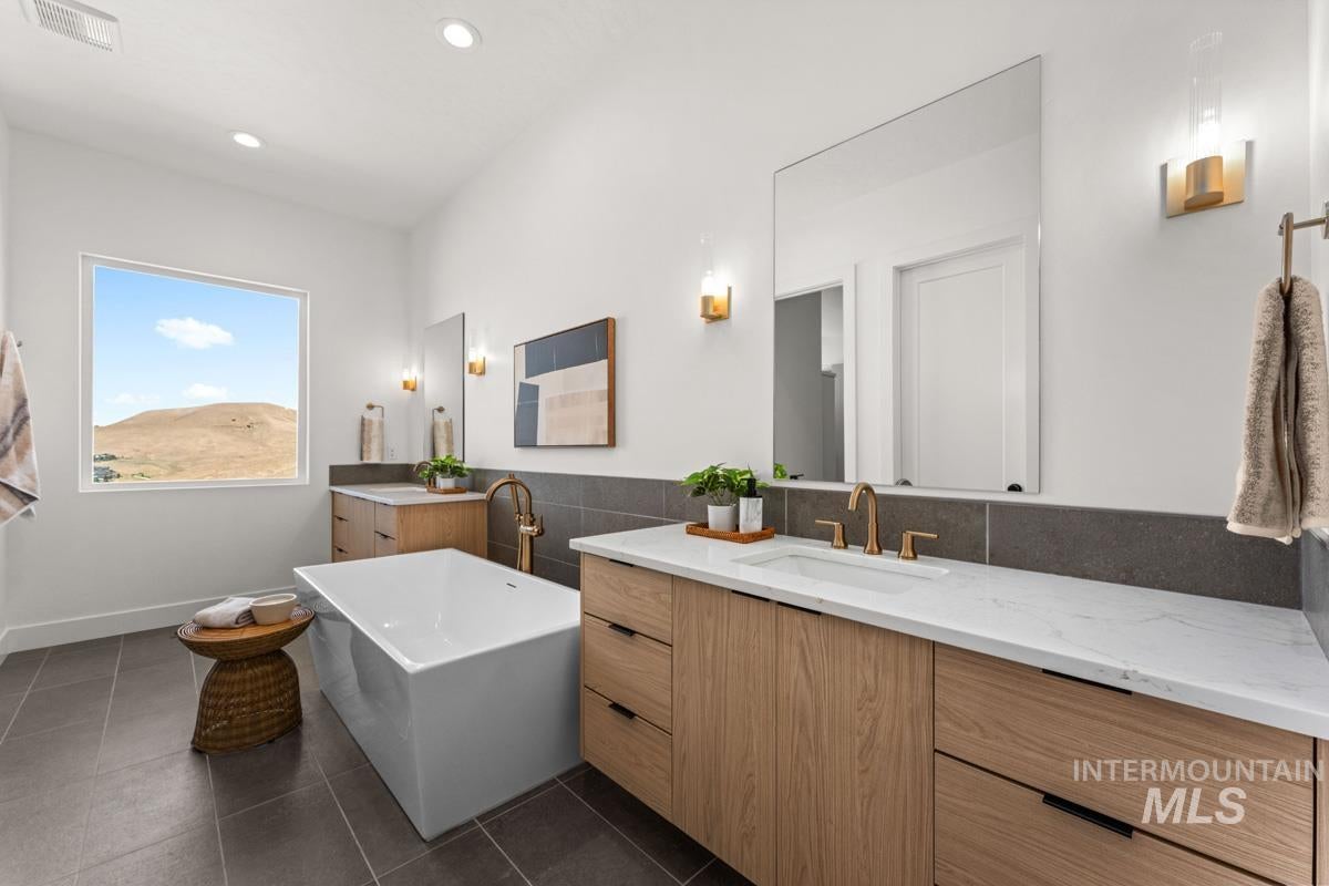 Spacious bathroom with a freestanding soaking tub, dual wood-finish vanities with undermount sinks, and white countertops