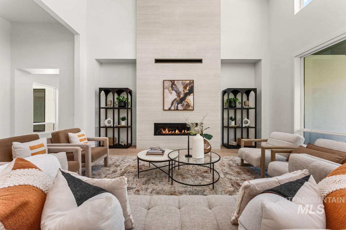Spacious living area featuring a floor-to-ceiling fireplace with an integrated linear firebox, high ceilings, large windows, and light wood-finish flooring