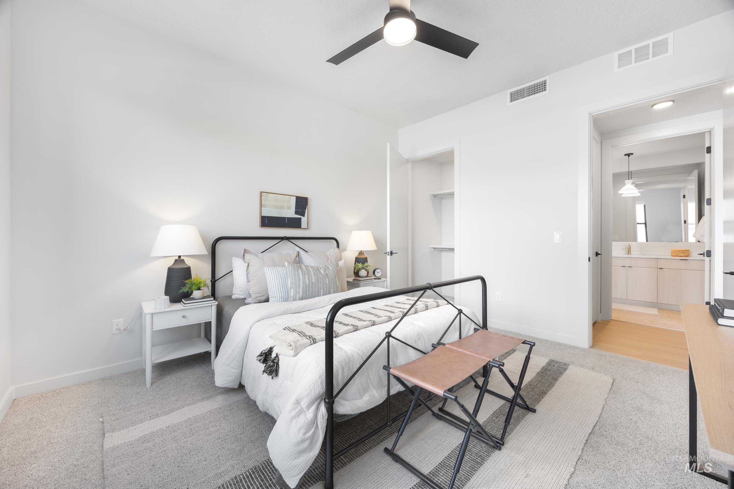 Bedroom with light carpet, a ceiling fan, and connected bathroom