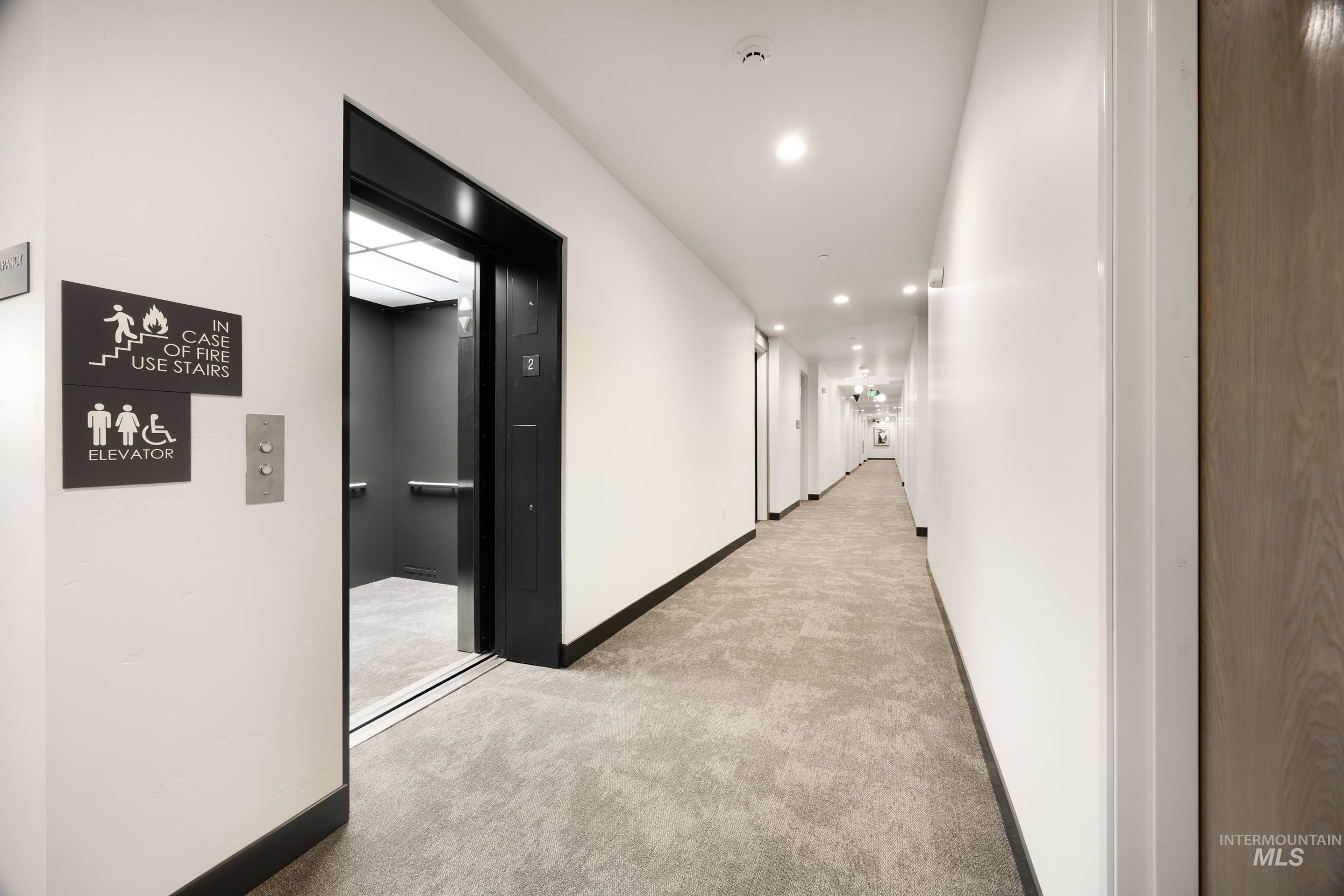 Corridor featuring carpet flooring, elevator, and recessed lighting