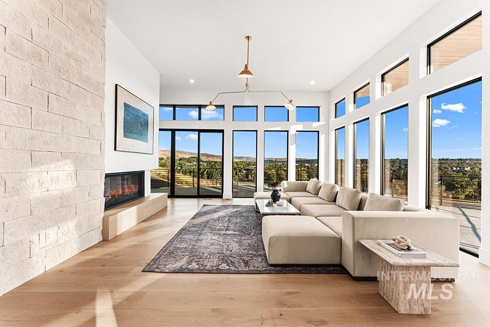Living area featuring light wood-type flooring, a glass covered fireplace, a towering ceiling, and recessed lighting