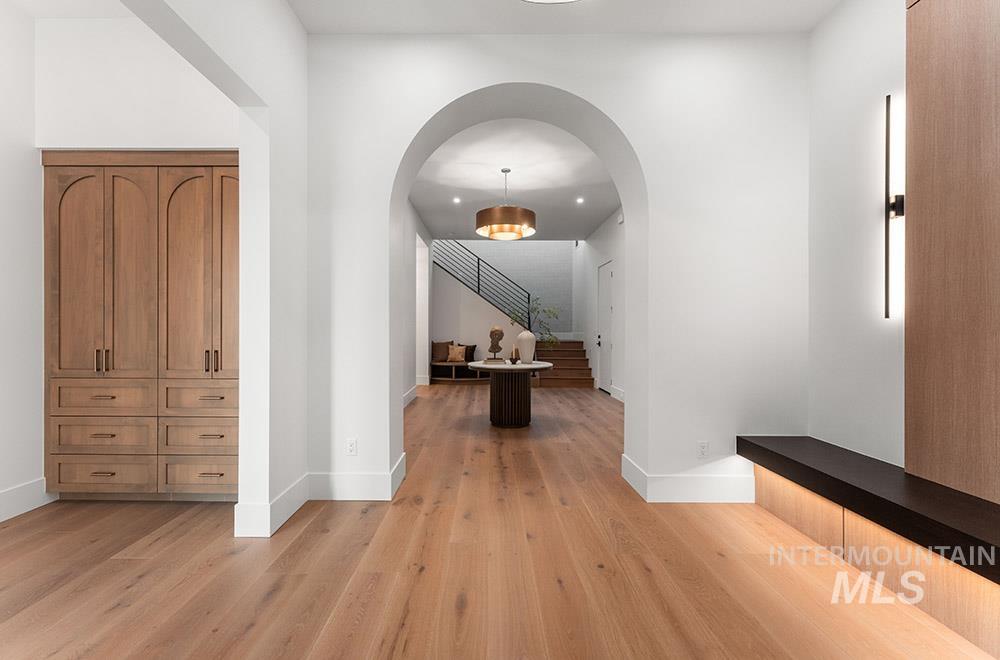 Hall with arched walkways, light wood-style floors, and stairway