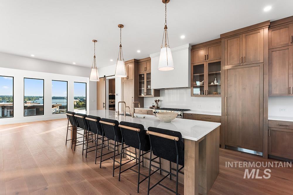 Kitchen featuring brown cabinetry, a kitchen bar, a large island, hanging light fixtures, and recessed lighting