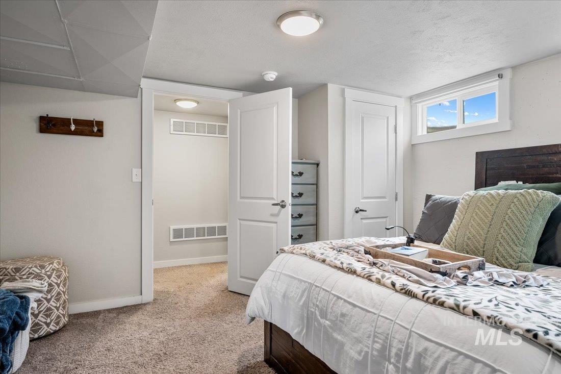 Bedroom with light colored carpet and a textured ceiling