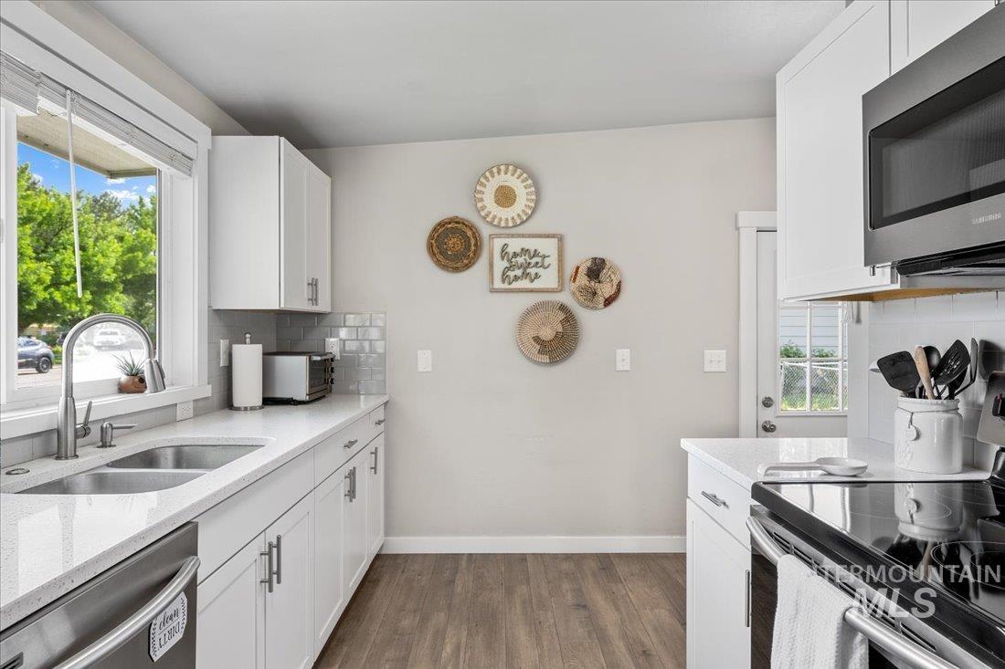 Kitchen with stainless steel appliances, dark wood-style flooring, plenty of natural light, and backsplash