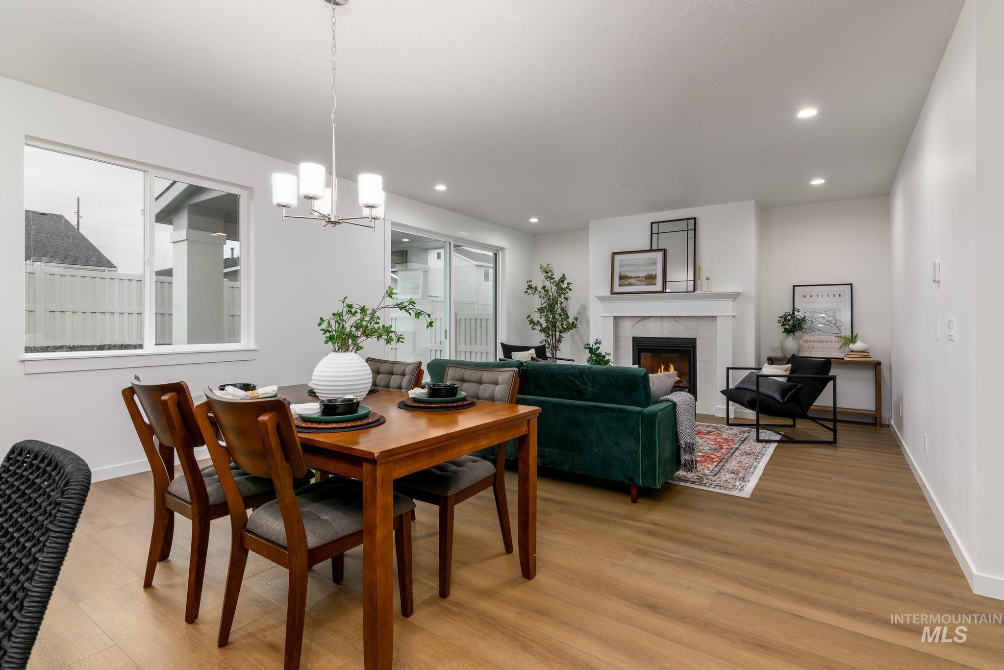 Dining room featuring a tiled fireplace, a chandelier, light wood-type flooring, and recessed lighting