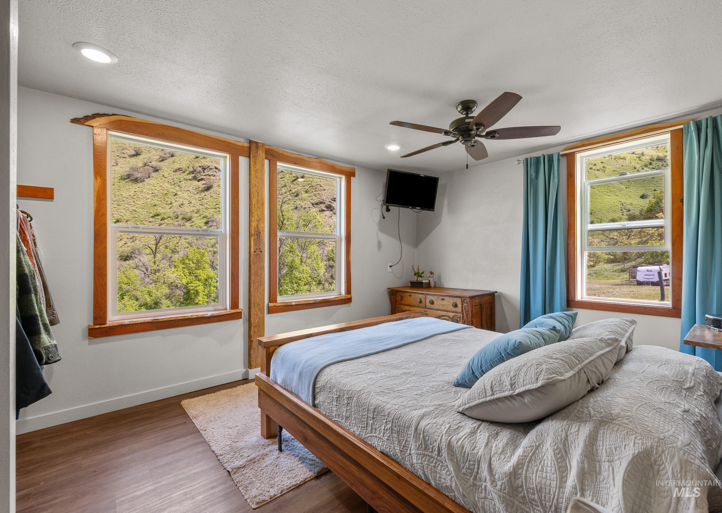 Bedroom featuring wood finished floors, multiple windows, a ceiling fan, a textured ceiling, and recessed lighting