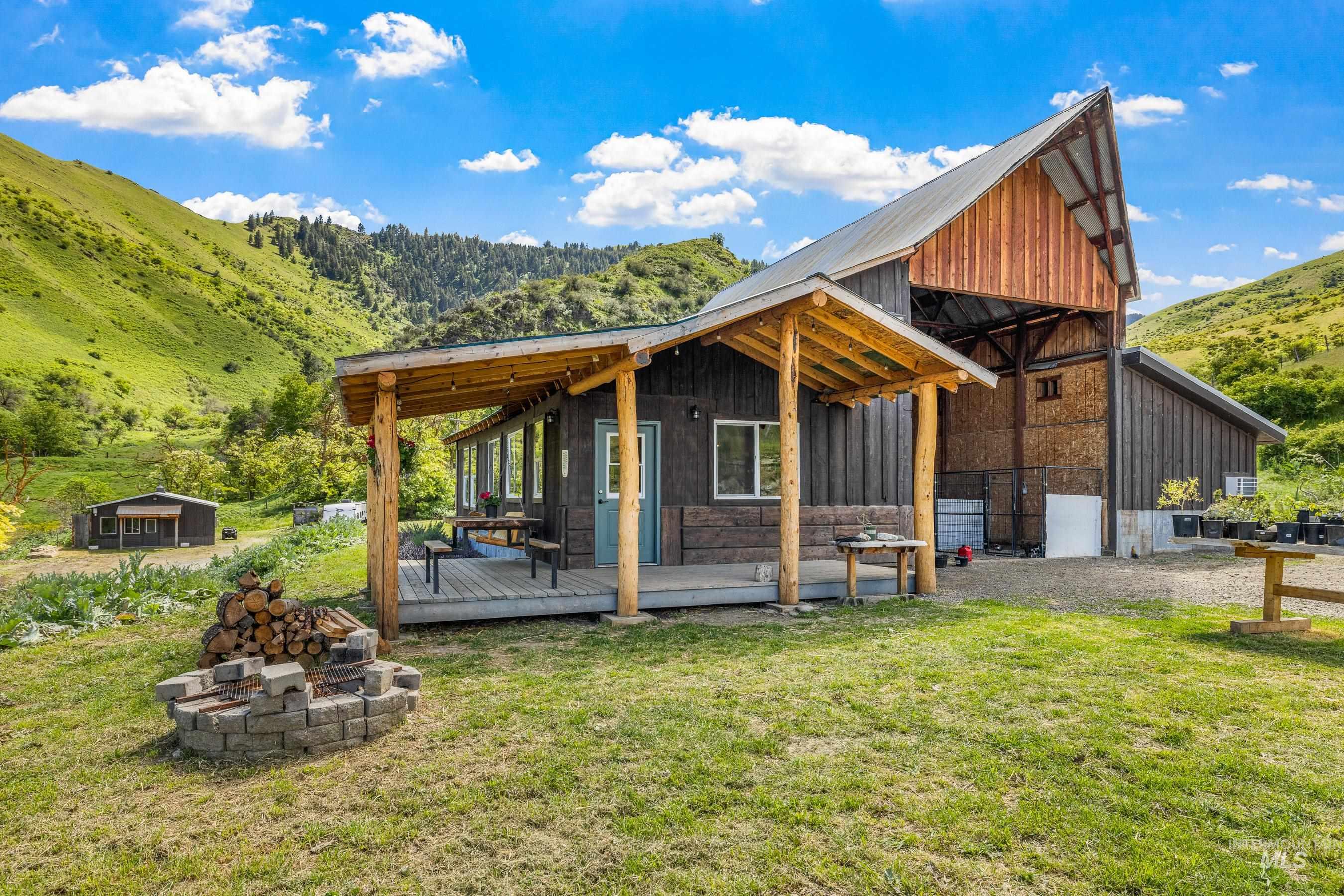 Guest Quarters - featuring an outdoor fire pit, a deck with mountain view, board and batten siding, a lawn, and an outdoor structure