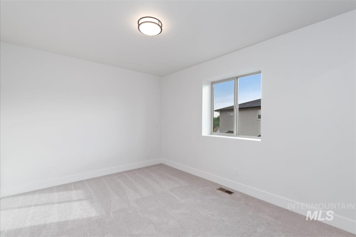 Empty room with light colored carpet and baseboards