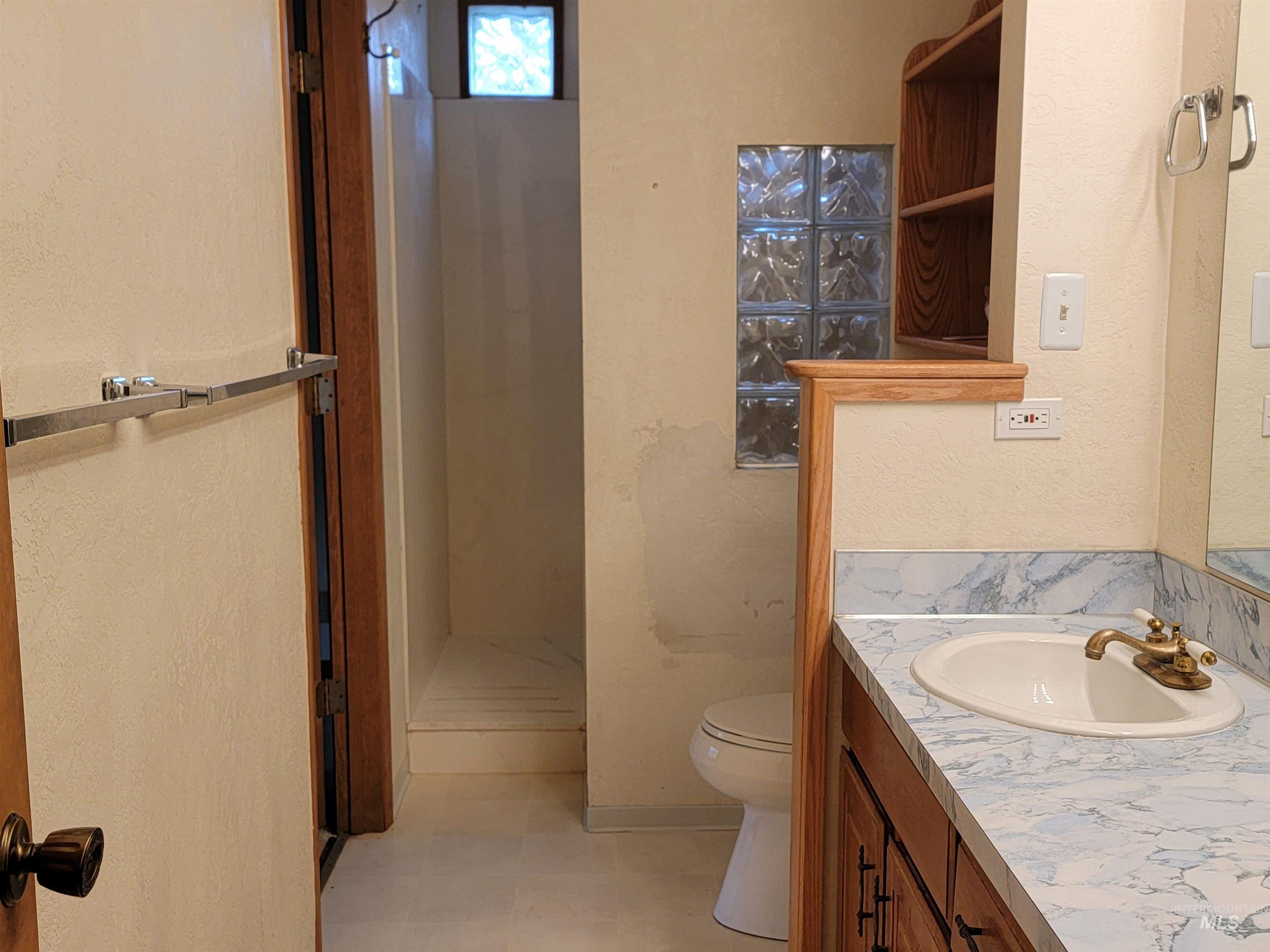 Bathroom with vanity, a shower stall, a textured wall, and light floors