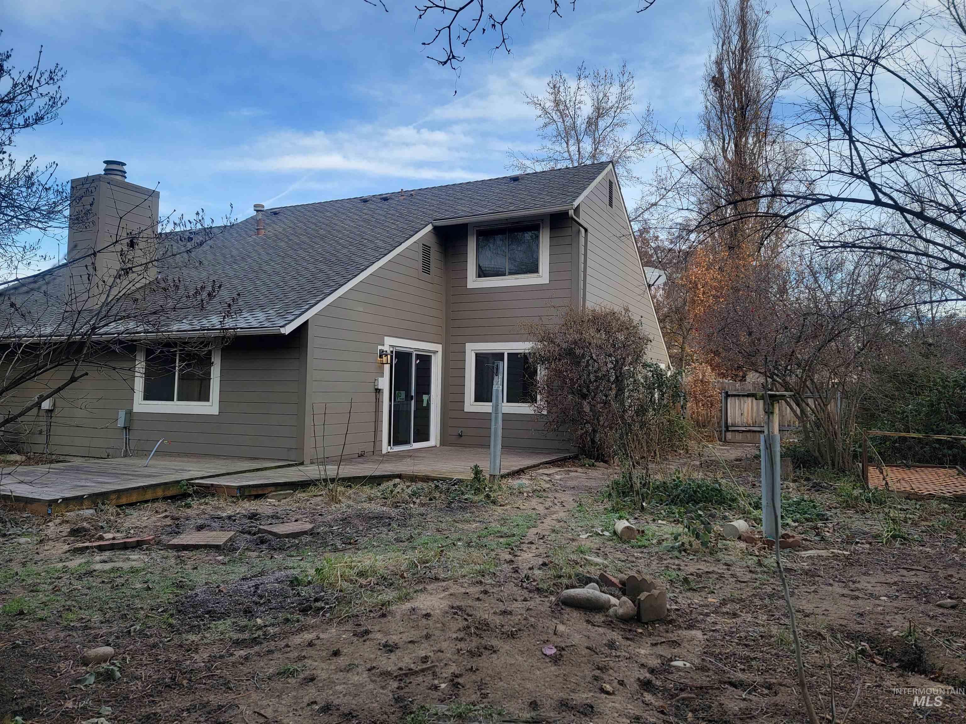 Back of property with a patio area, a chimney, and a shingled roof
