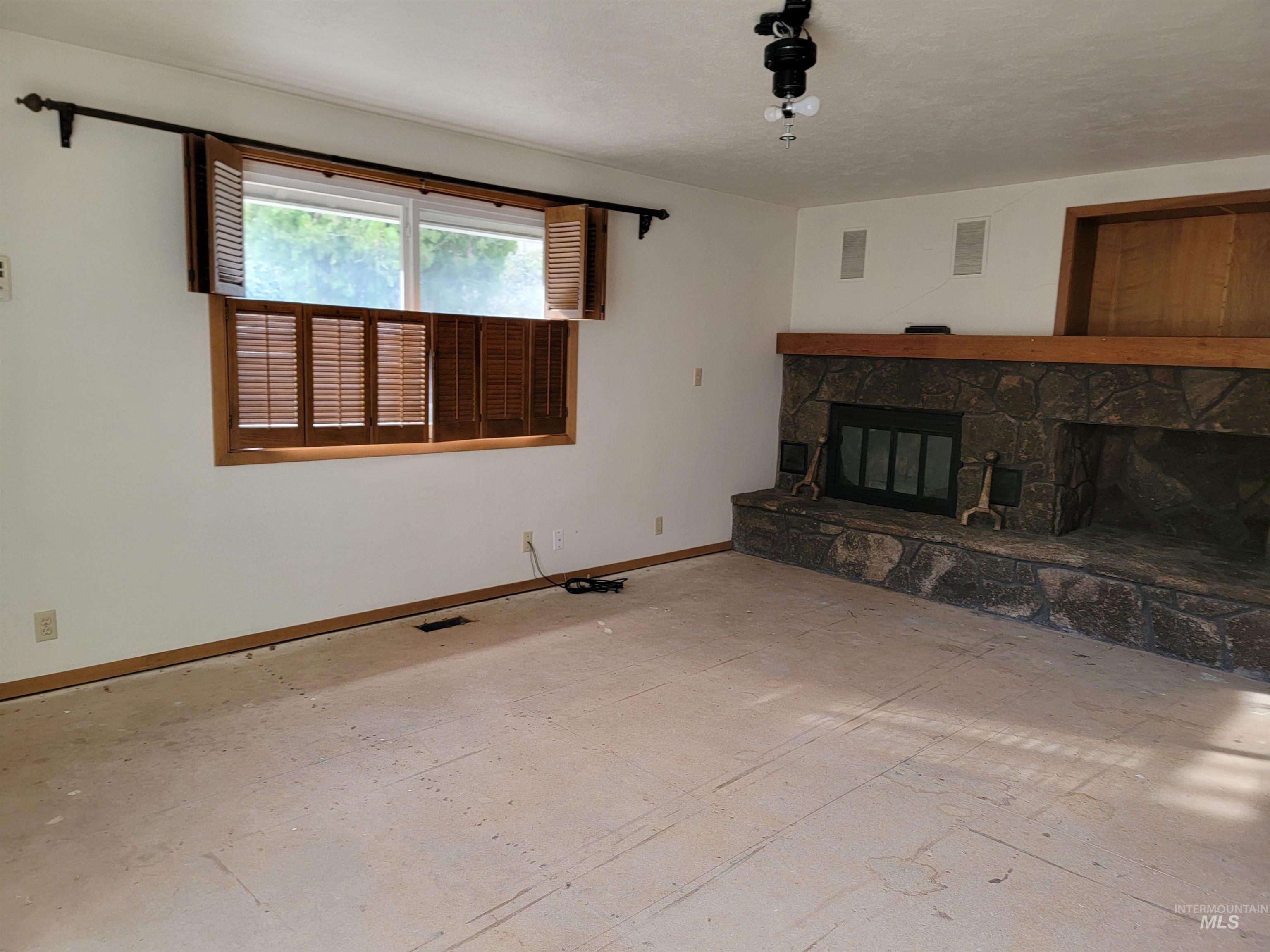 Unfurnished living room featuring a fireplace and baseboards