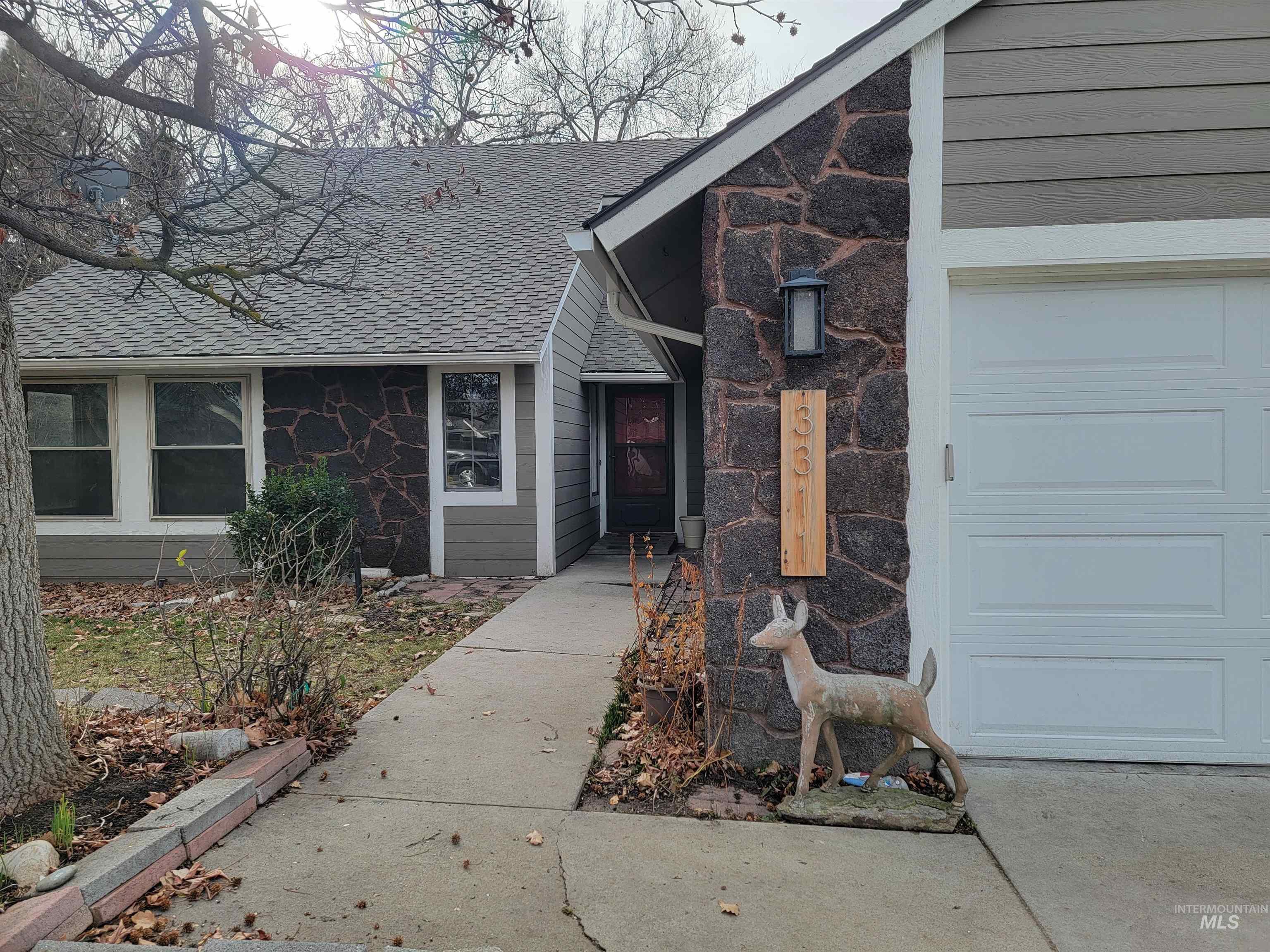Entrance to property featuring stone siding and a shingled roof
