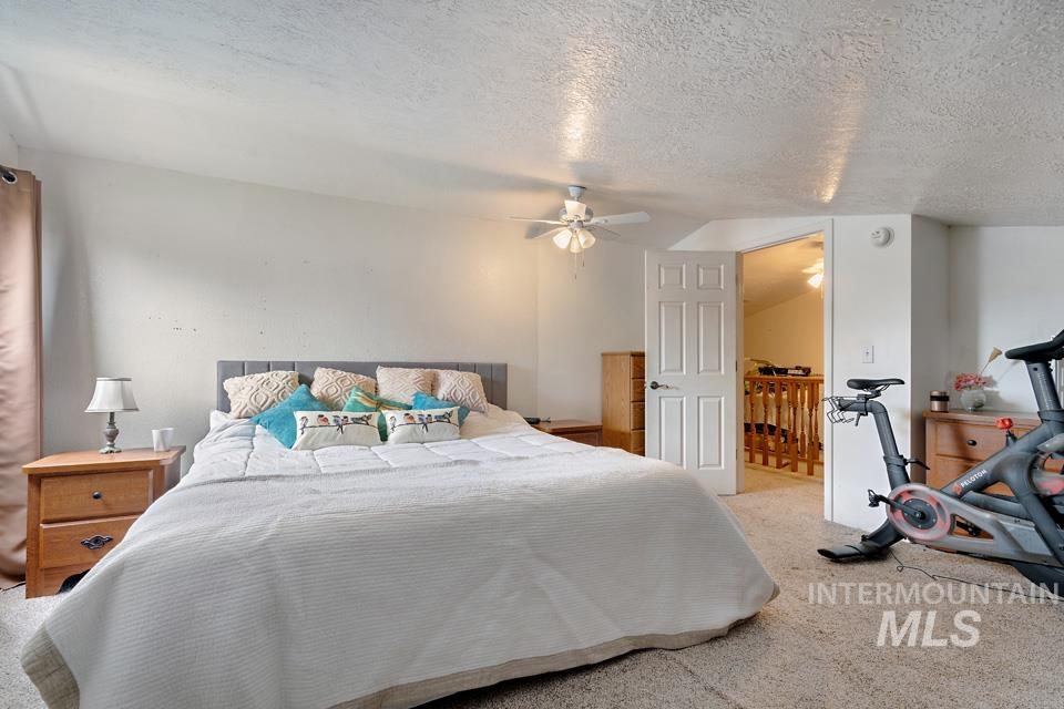 Bedroom with carpet flooring, a textured ceiling, ceiling fan, and vaulted ceiling