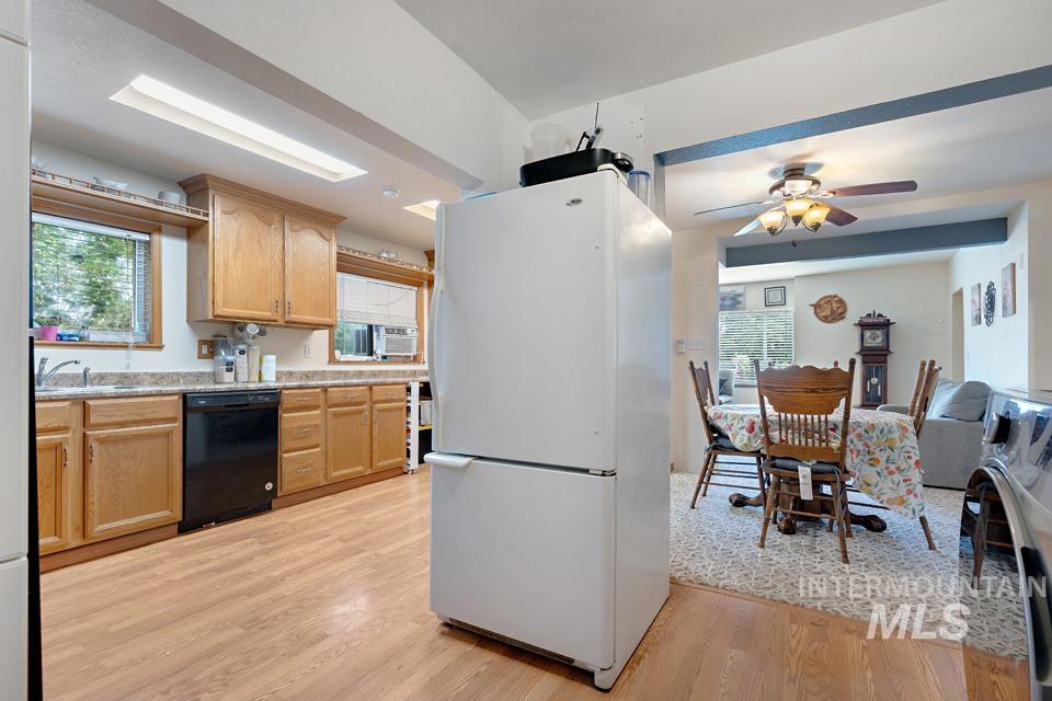 Kitchen with freestanding refrigerator, healthy amount of natural light, black dishwasher, and light wood-style floors