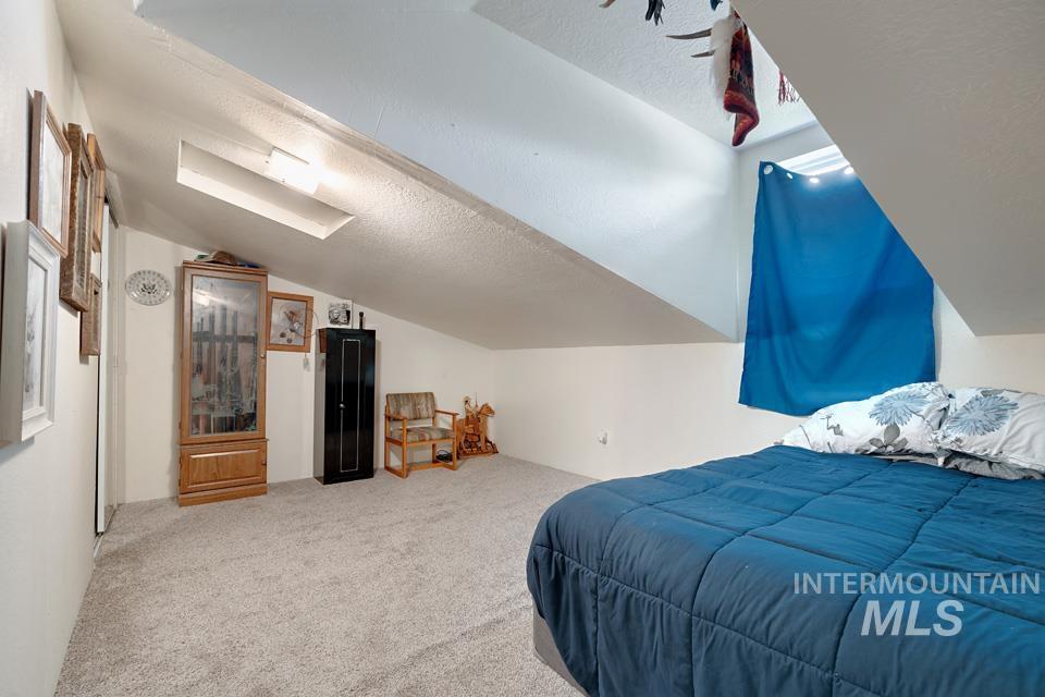 Bedroom featuring lofted ceiling, a textured ceiling, and carpet floors