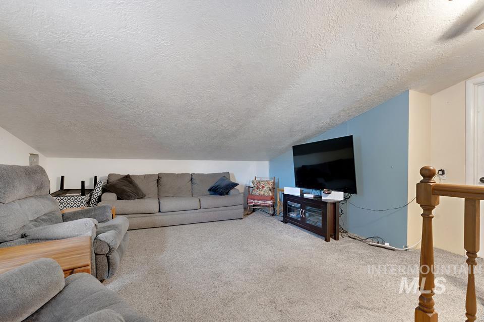 Carpeted living area with a textured ceiling and vaulted ceiling