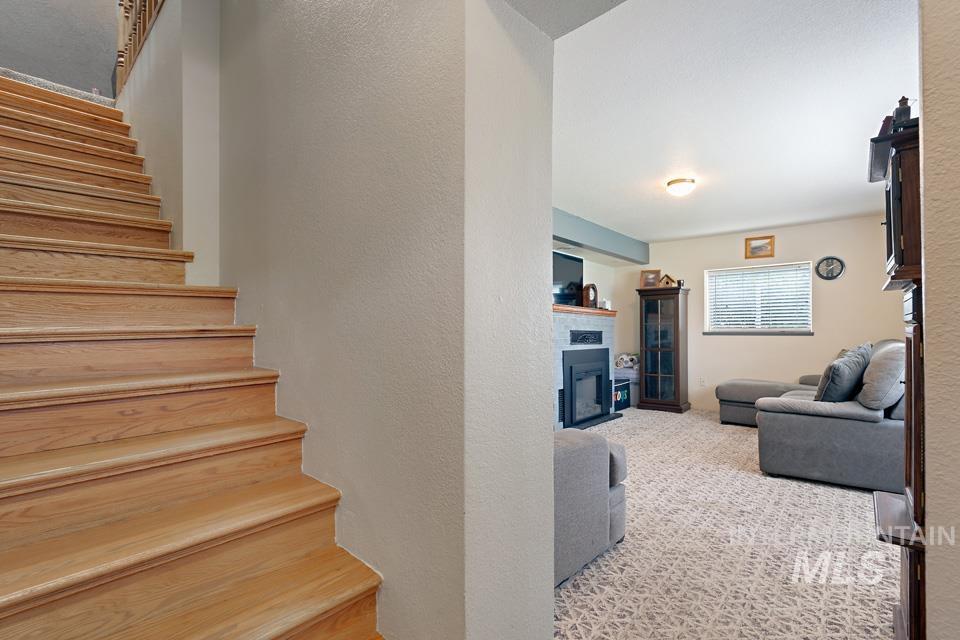 Stairway with a fireplace, a textured wall, and carpet