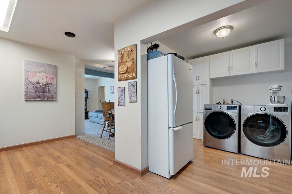 Laundry room featuring cabinet space, light wood finished floors, and washer and clothes dryer