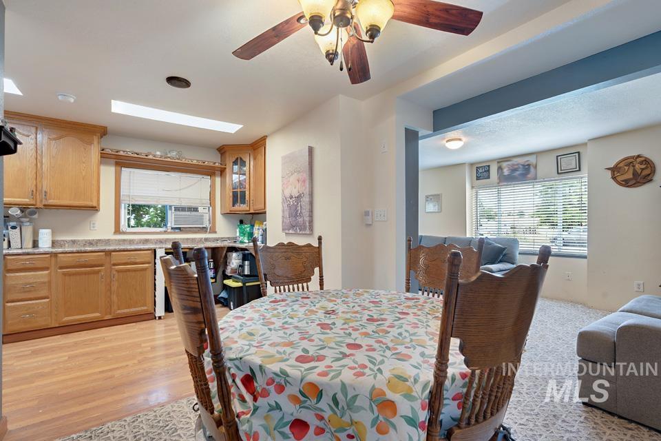 Dining room with a skylight, ceiling fan, and light wood finished floors