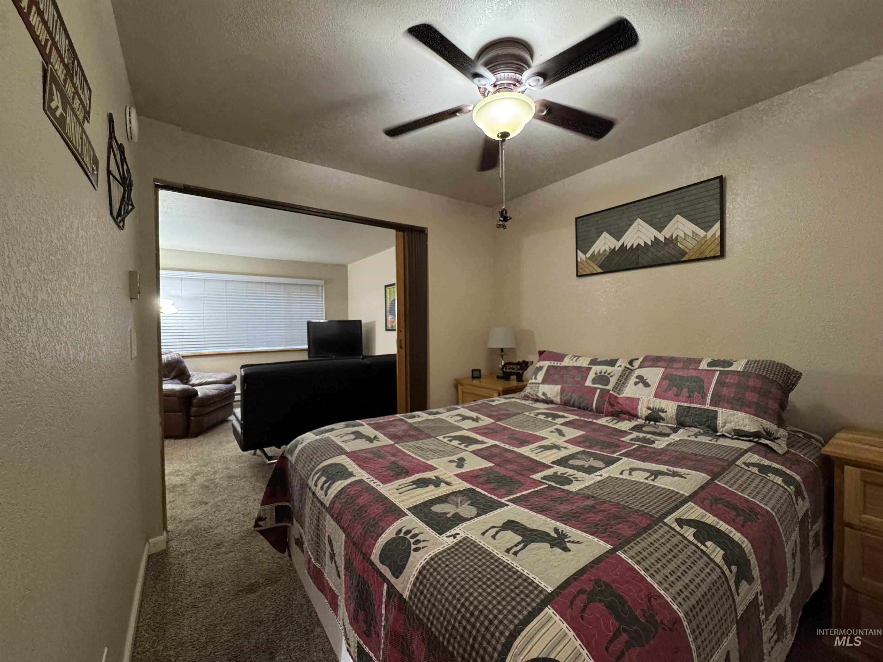 Carpeted bedroom with a textured wall, a ceiling fan, and a textured ceiling