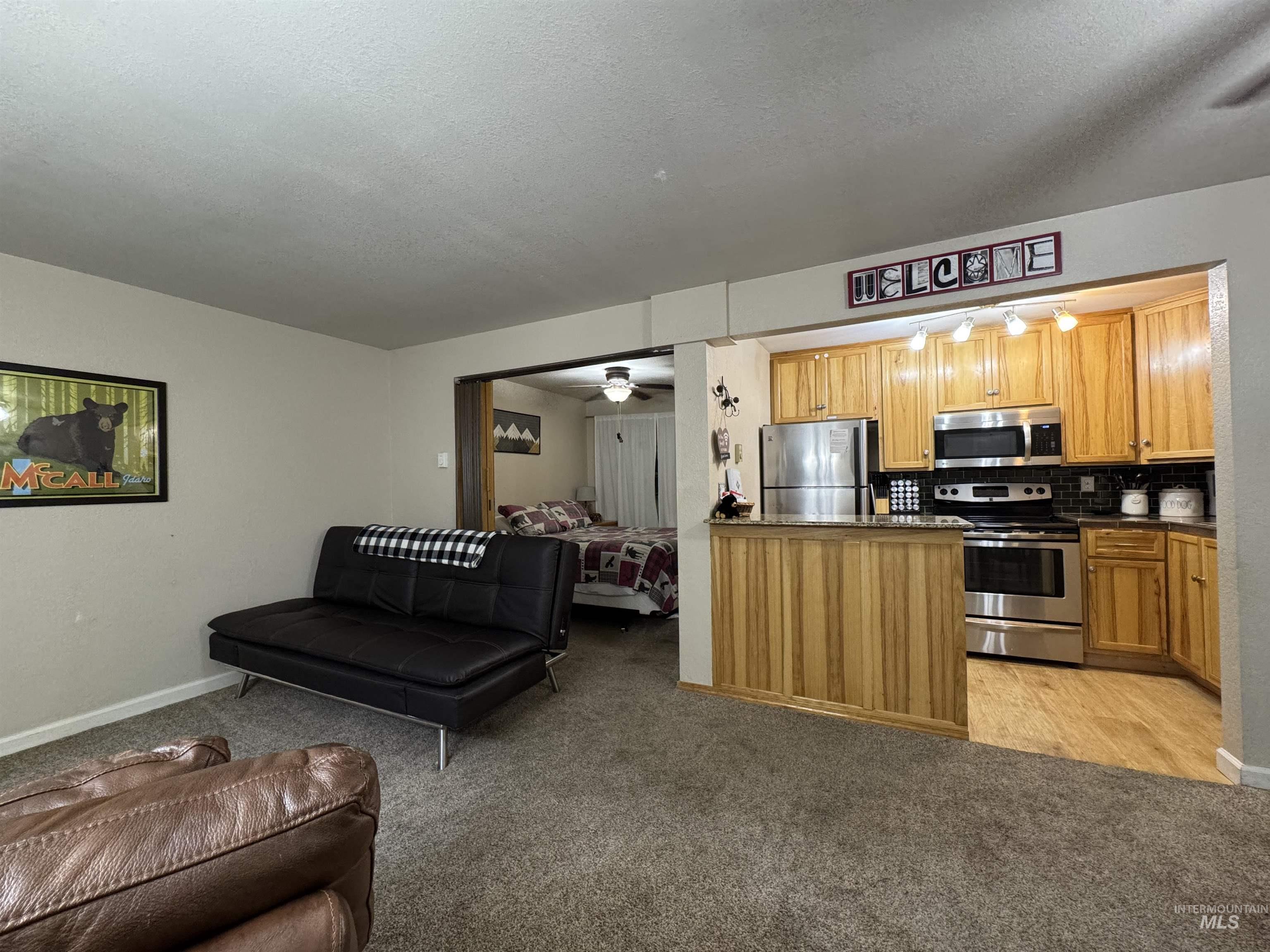Living room featuring a ceiling fan, light carpet, and open floor plan.