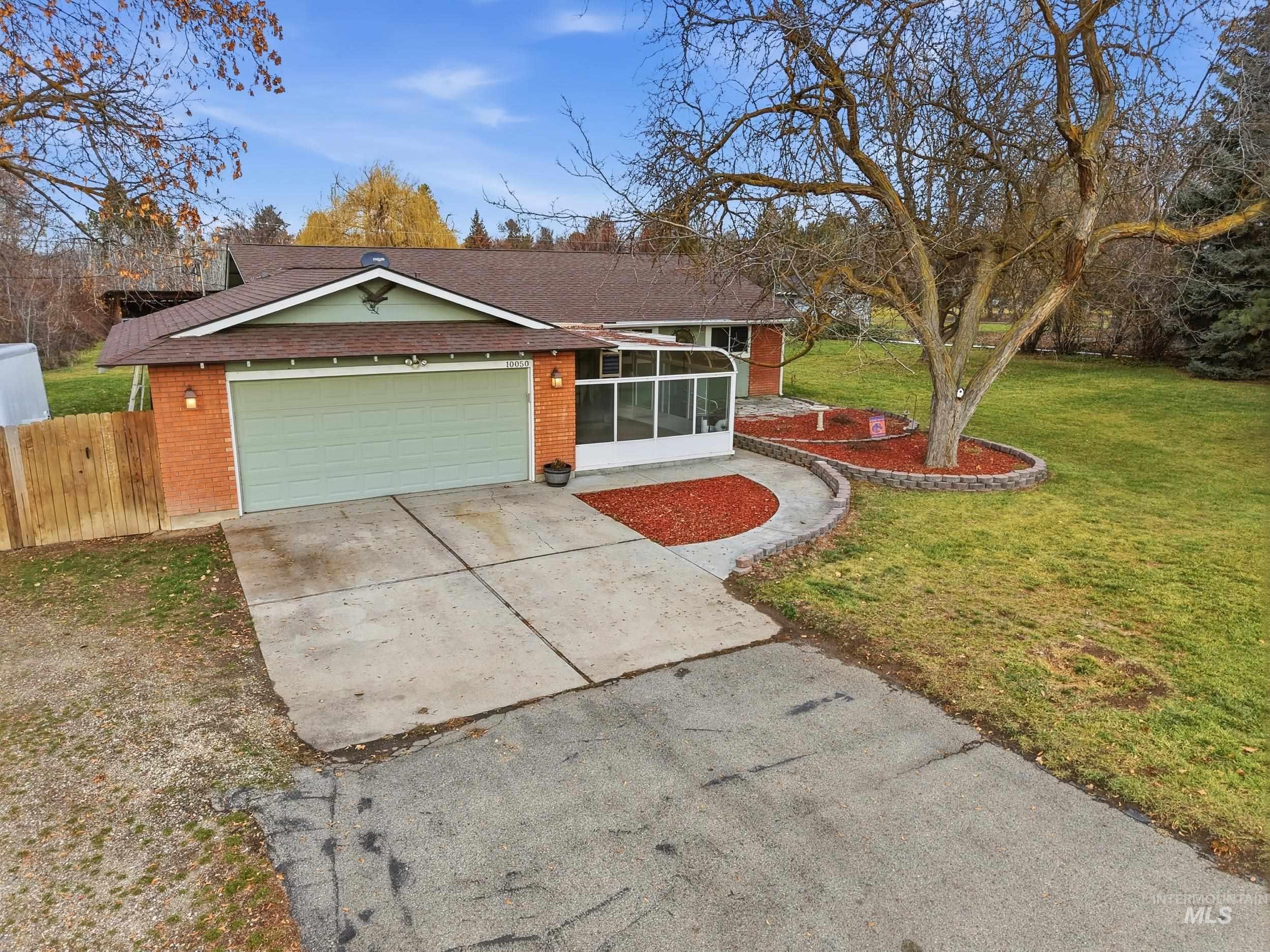 View of front of property featuring roof with shingles, concrete driveway, a sunroom, an attached garage, and brick siding