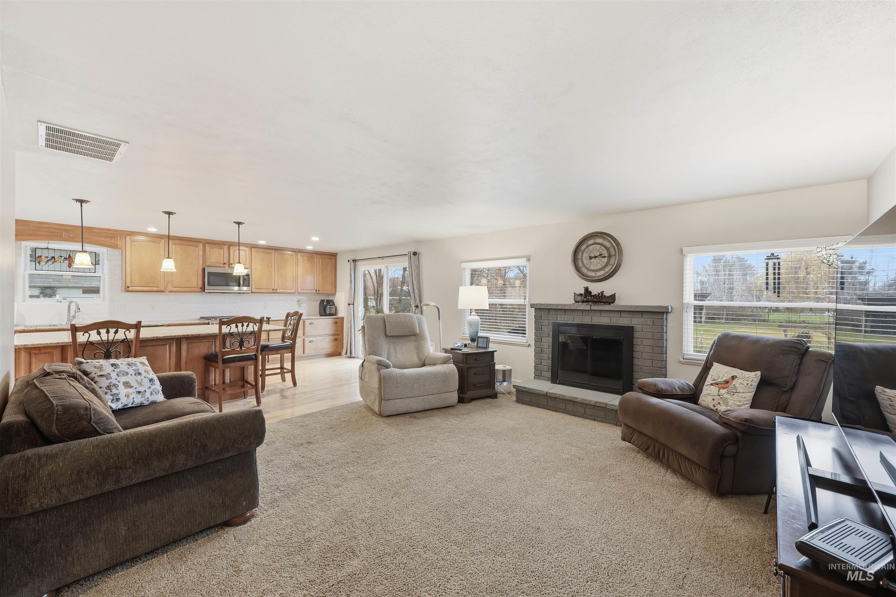 Living room with a fireplace, recessed lighting, and light colored carpet