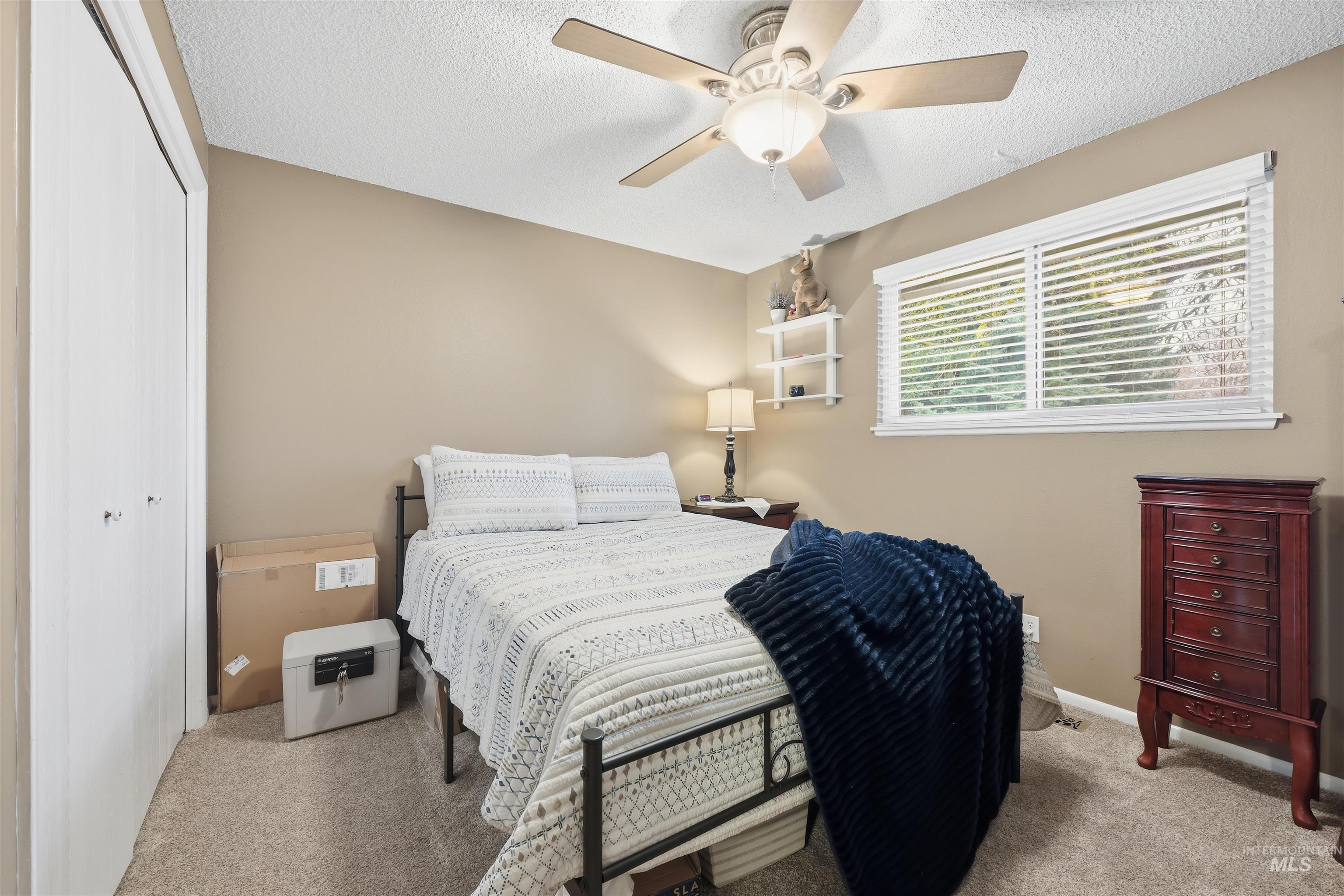 Bedroom featuring a closet, a textured ceiling, light carpet, and ceiling fan