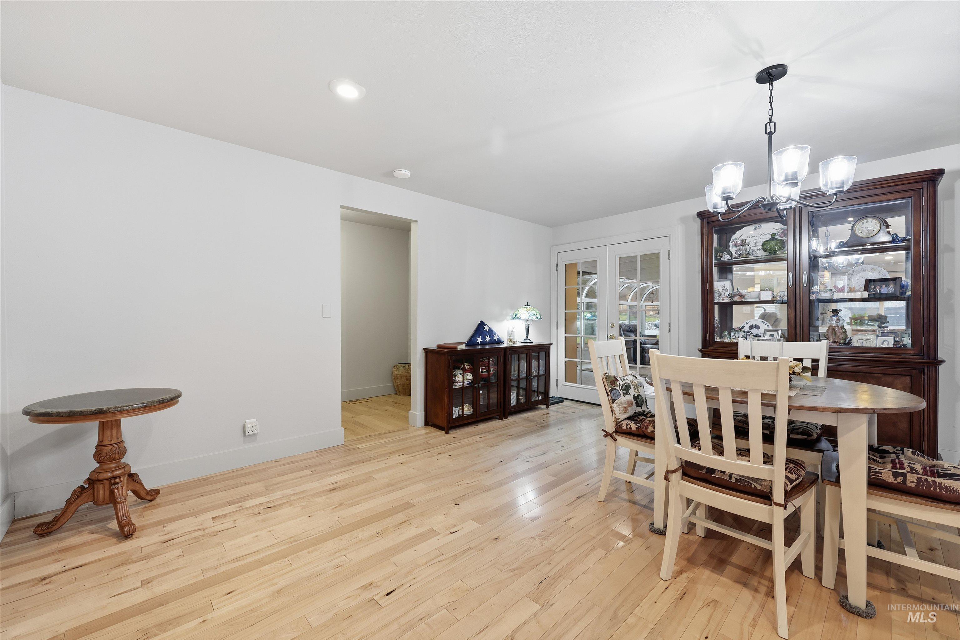 Dining space with a chandelier, light wood finished floors, and french doors