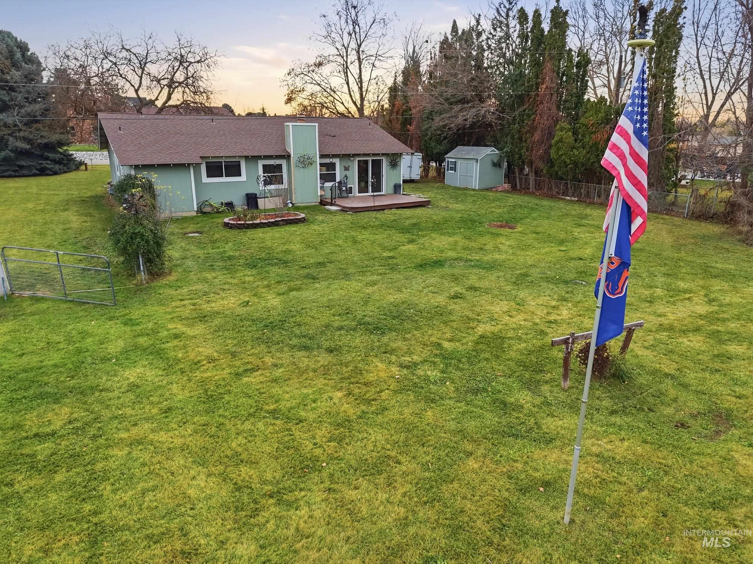 Rear view of house with a storage unit, a fenced backyard, a wooden deck, and roof with shingles
