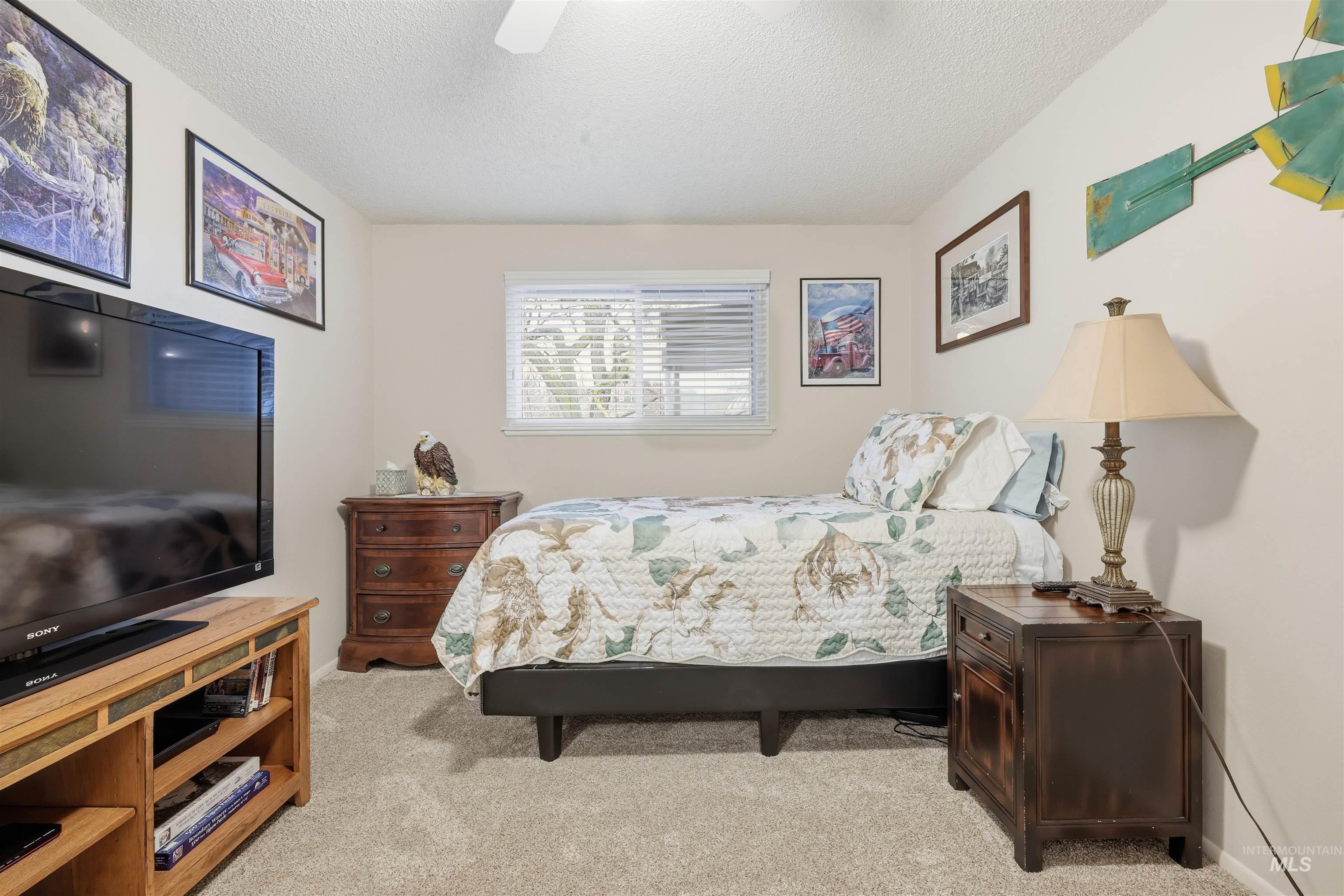 Bedroom featuring light carpet, a textured ceiling, and ceiling fan
