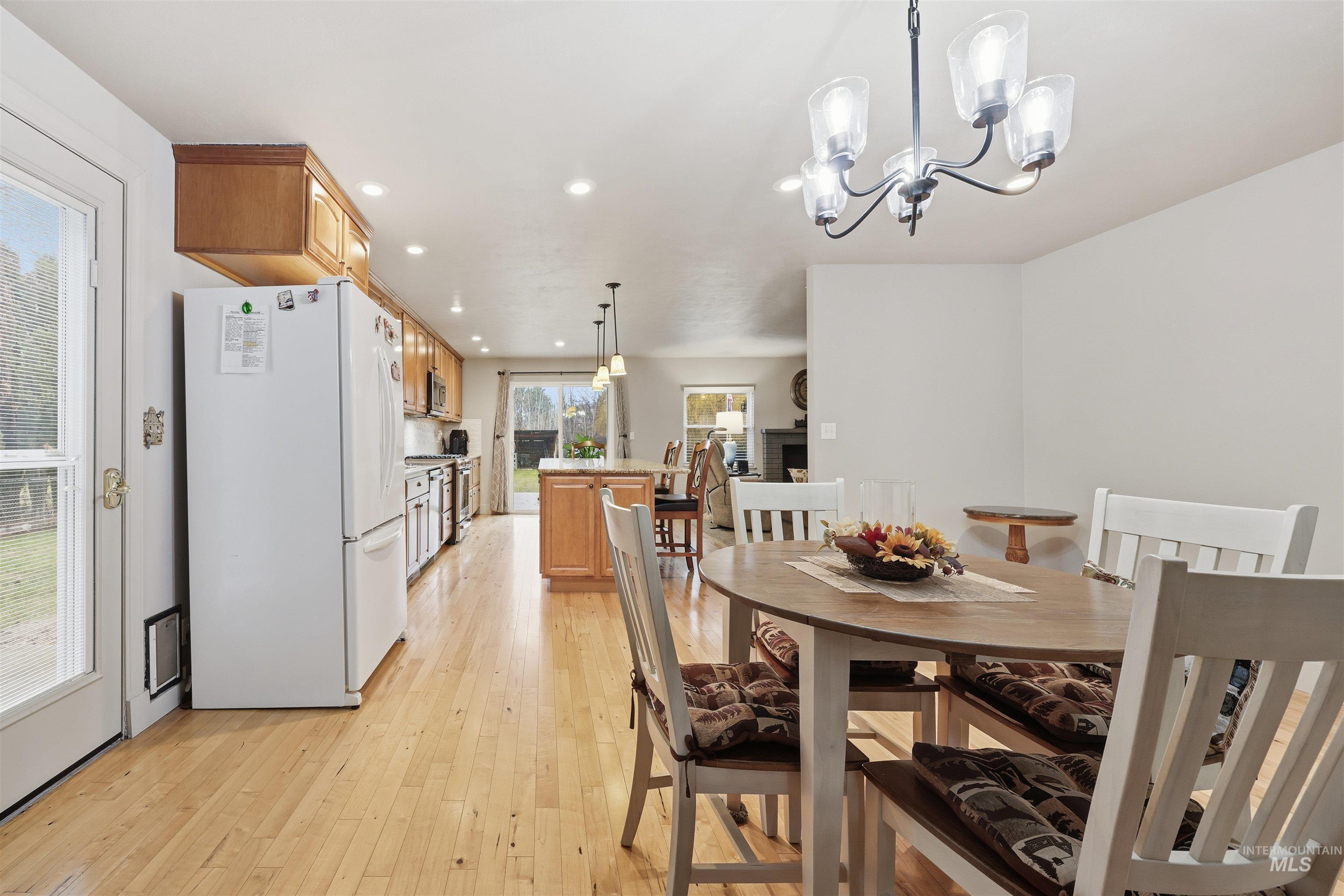 Dining room with light wood-style floors, recessed lighting, a chandelier, and a fireplace