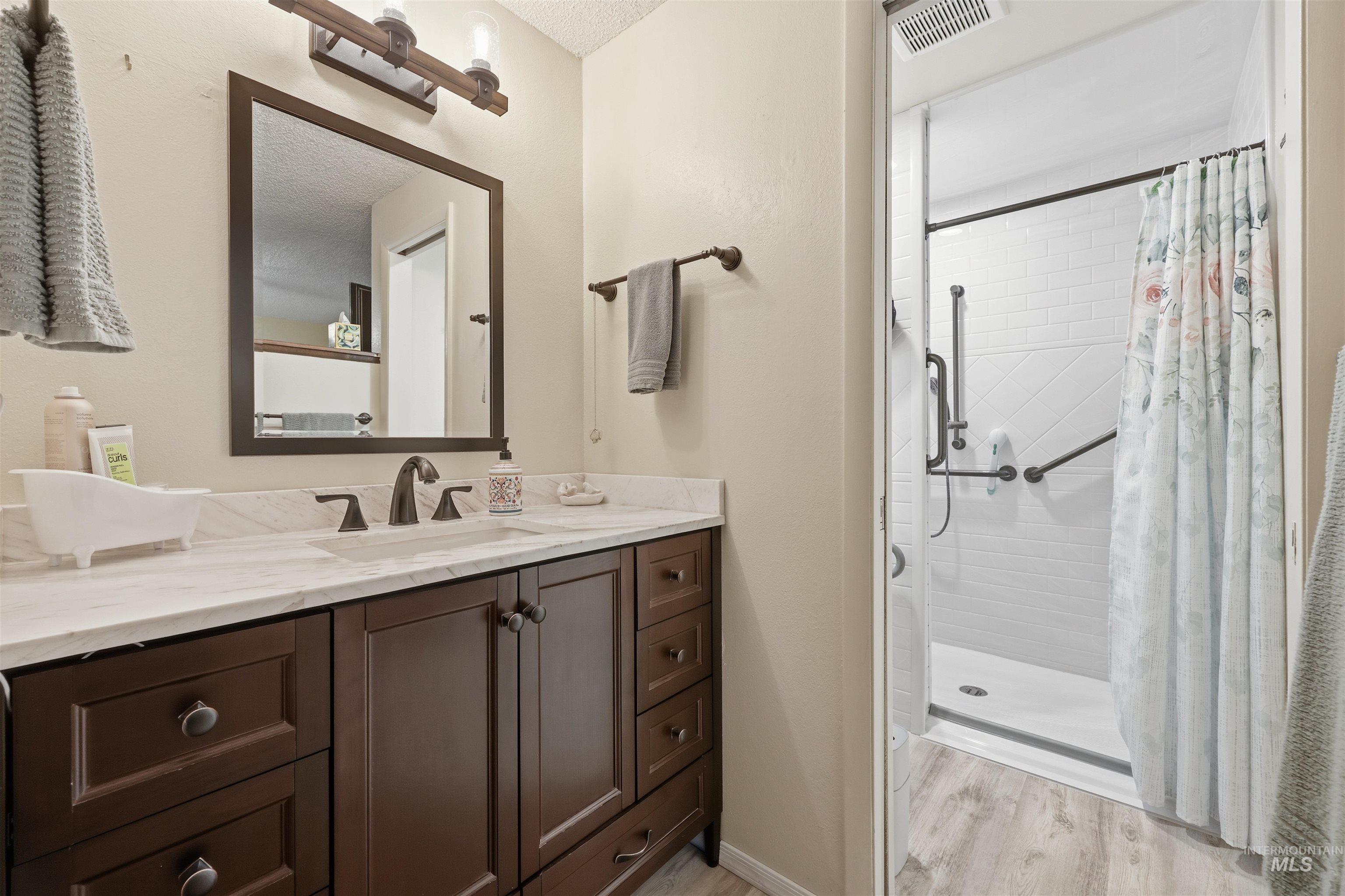 Primary Bathroom featuring vanity, a stall shower, and light wood-style flooring