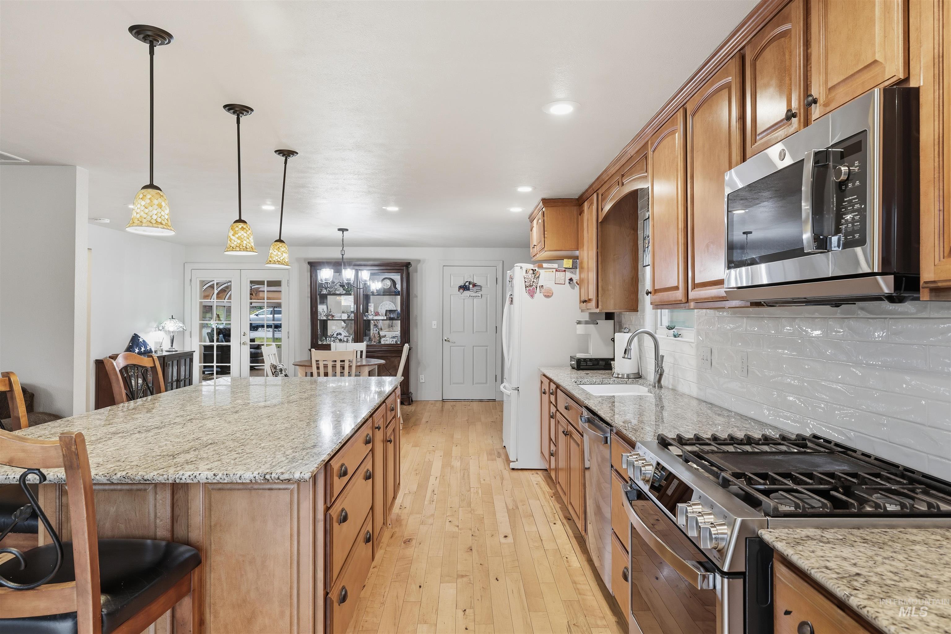 Kitchen featuring a breakfast bar, light Granite counters, stainless steel appliances, hanging light fixtures, and recessed lighting