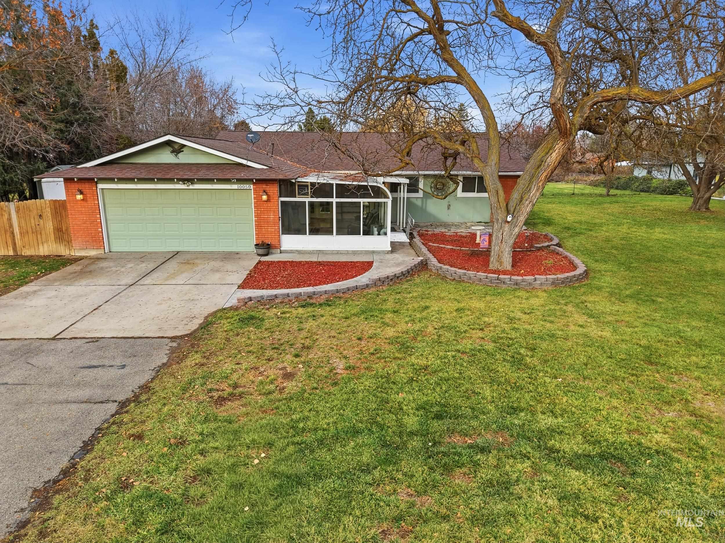 Ranch-style house with a sunroom, driveway, roof with shingles, an attached garage, and brick siding