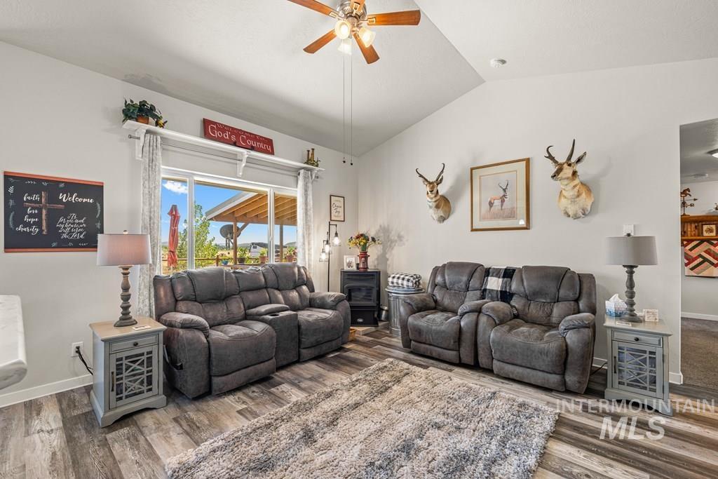 Living area with lofted ceiling, a ceiling fan, and wood finished floors