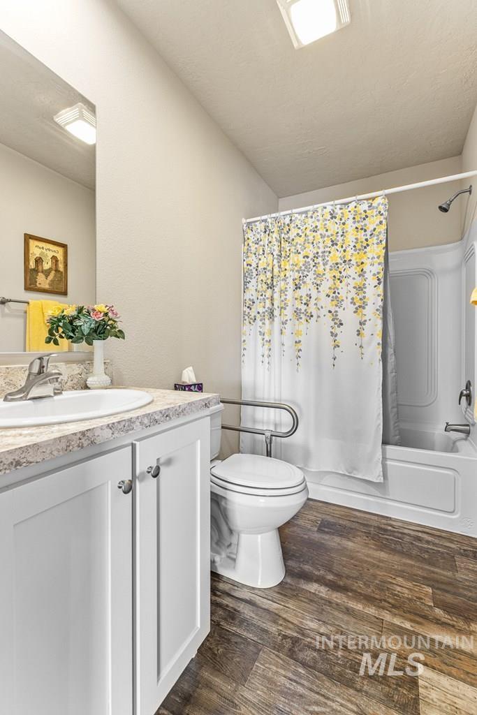 Bathroom with shower / bath combination with curtain, vanity, and dark wood-style floors